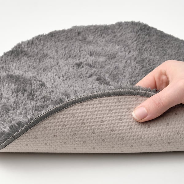 Hand touches soft, grey MALÖRTSMOTT chair pad, showing its warm, comfortable, and non-slip.