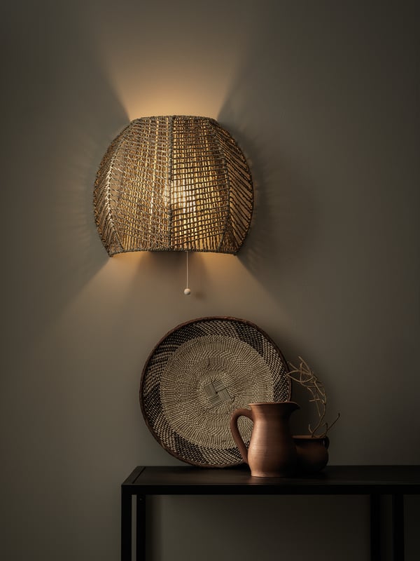 Hand-braided wall lamp, natural sedge, warm multi-directional light, rustic earthy tones, cosy atmosphere.