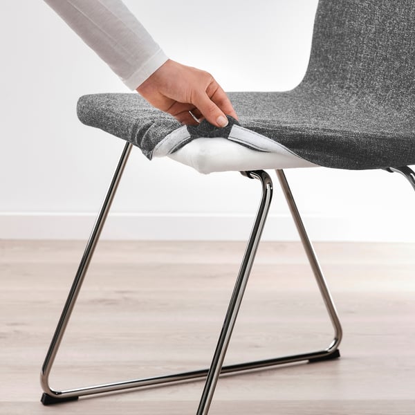 Person placing round, grey MARIEDAMM chair cover over seat.