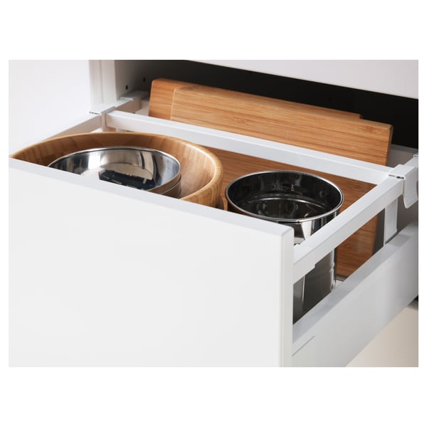 White kitchen drawer pulled out fully, showcasing three stainless steel bowls and wooden cutting boards, demonstrating its full-extension feature.