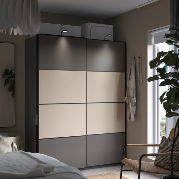 Modern bedroom black and beige sliding wardrobe, wicker chair, and window.