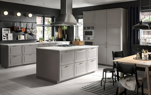 Modern grey kitchen with white island; sleek cabinets, stainless steel appliances, hanging lights, wooden floor.