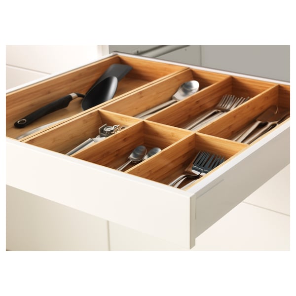 Bamboo cutlery organiser in white drawer, neatly storing utensils, including spoons, forks, and knives.