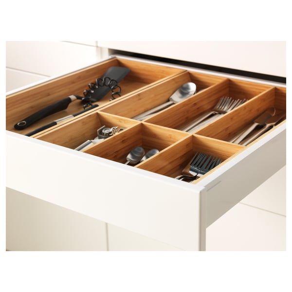 Organised kitchen drawer with compartments, holding utensils, neatly arranged in sections, featuring self-closing mechanism.
