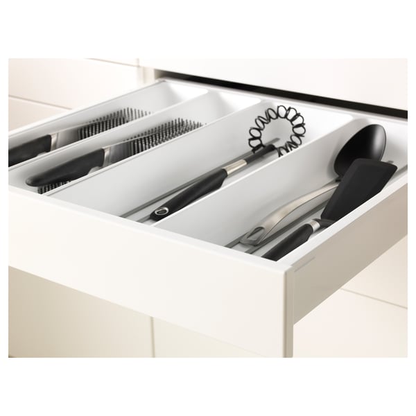 White kitchen drawer with black utensils, including knives, whisk, and slotted spoon, organised in compartments.