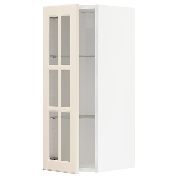 Off-white METOD kitchen cabinet with glass doors, bevelled edges, nickel hinges, and glass shelves.