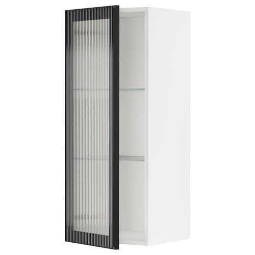Displays a white METOD kitchen cabinet with a black hejsta glass door, featuring a reeded glass design and a sleek metal frame.