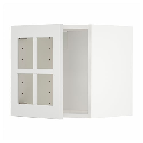 Depicts a white METOD kitchen cabinet with glass doors, featuring a modern, sleek design with a sturdy frame.