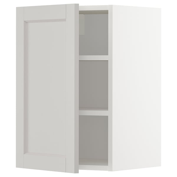 A white METOD kitchen cabinet with light grey shelves and bevelled edges.