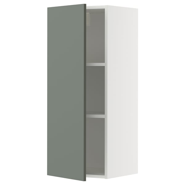 A METOD wall cabinet in white with a grey-green door. It has two shelves inside and is modern in design.