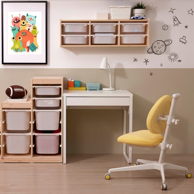 A kids study area with a small white desk, yellow chair, and storage.