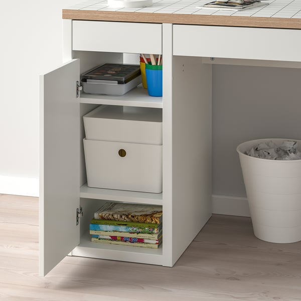 White desk with open cabinet showing storage boxes, books, and pencil holders, featuring adjustable shelves for organised storage.