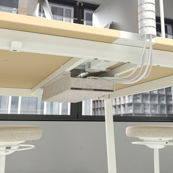 A high conference table with built-in cable management for keeping devices charged, and a footrest for leg support during meetings or calls.