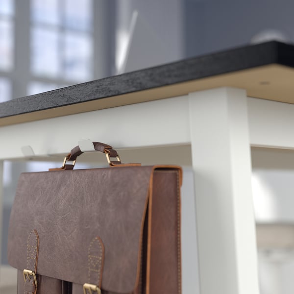 Brown leather bag hangs on high table hook, ideal for meetings and storage.