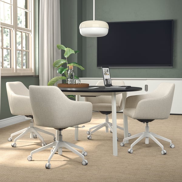 Modern conference setup with MITTZON round table, beige chairs, and large tv.