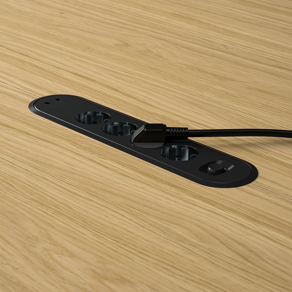 Black MITTZON table socket with cable management tray on wooden table.