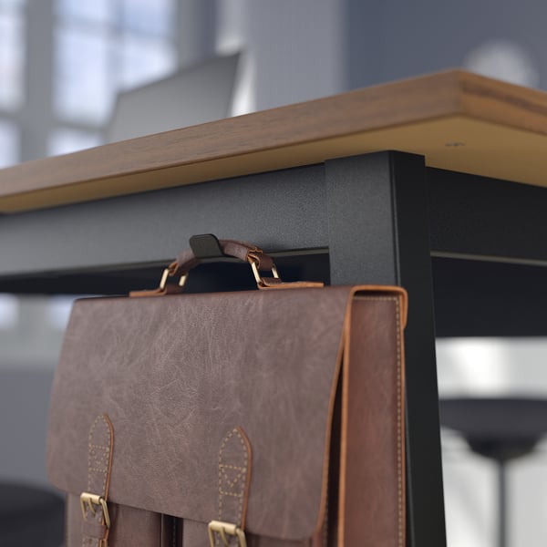 A leather bag hangs on a high tables hook, designed for standing or sitting meetings.
