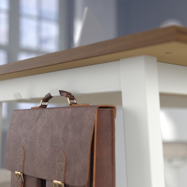 Brown leather bag hangs from a hook on a high conference table designed for sitting or standing.