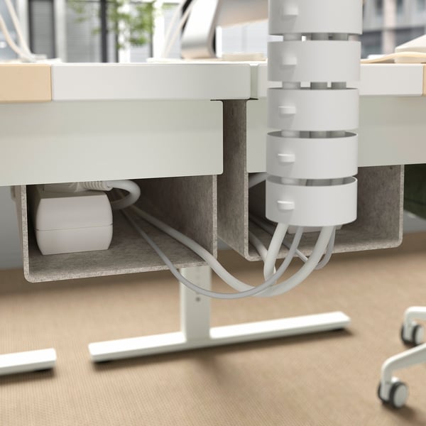Cable management tray under an adjustable desk holds and organises wires efficiently.