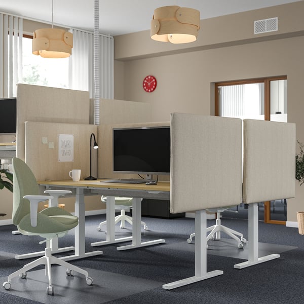 Modern office with MITTZON stand desks, green chairs, beige dividers, red clock, wooden lamps. Desks are larger, centrally placed.