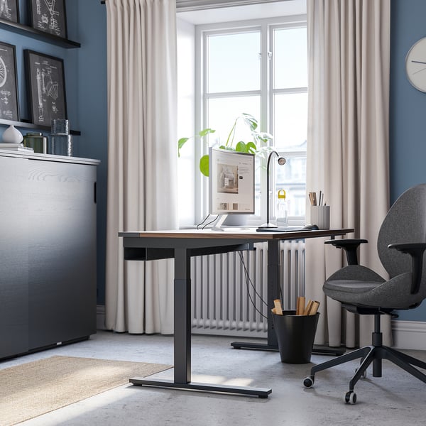 Modern home office with adjustable desk, ergonomic chair, and storage unit.