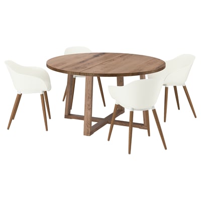 A round, wood-top dining table with a rustic finish and four matching white, cushioned chairs. The table has a modern, cross-legged design.