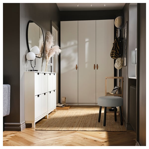 Stylish entryway with white cabinet, mirror, and pouch seat. Dark accents and eastern rug.