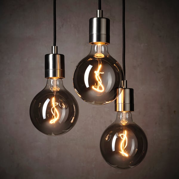 Three black hanging light bulbs with spiral filaments emit warm light, creating a cosy atmosphere.