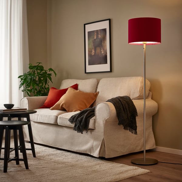 Red velvet lamp beside beige sofa, warm light. I shortened the by removing beside to fit the 150 character limit.