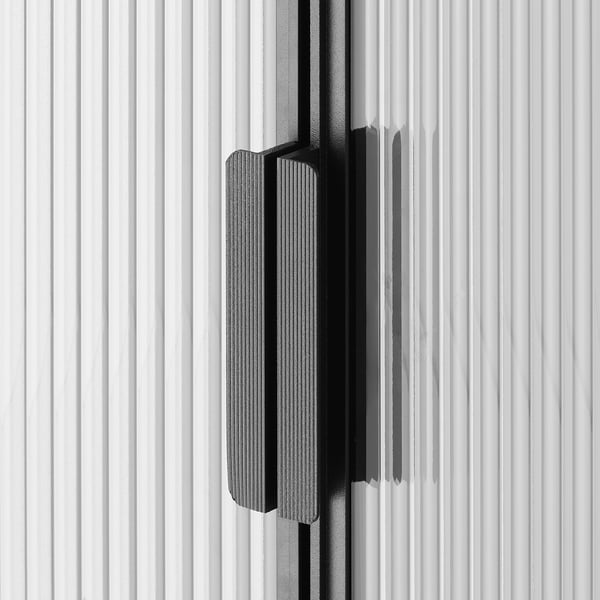 Black and white close-up of sleek, modern cabinet door with textured glass and minimalist handle.