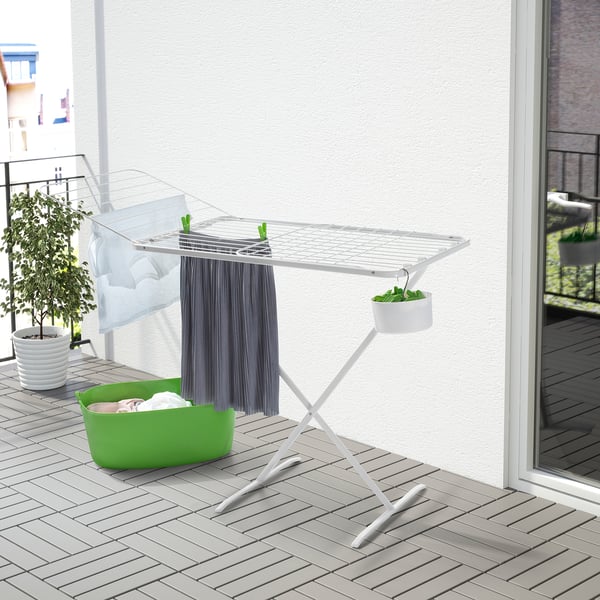 Multi whites drying rack with wings on balcony, surrounded by plants and a green basket, sturdy with 4 hooks.