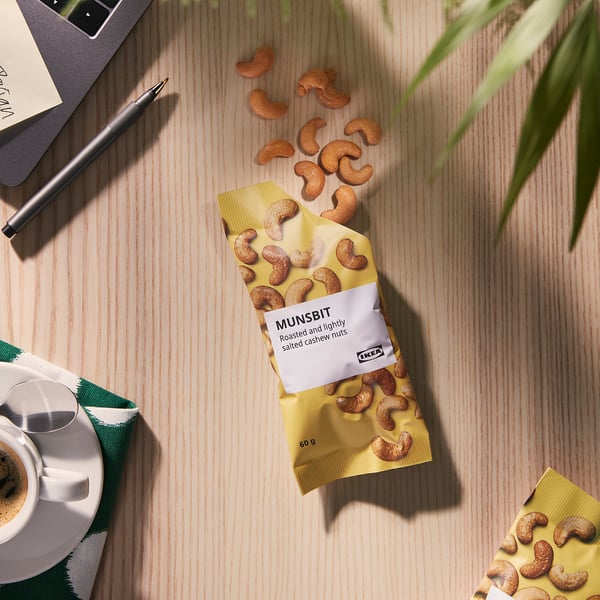 Bag of IKEA MUNSBIT cashew nuts on desk with coffee and notebook