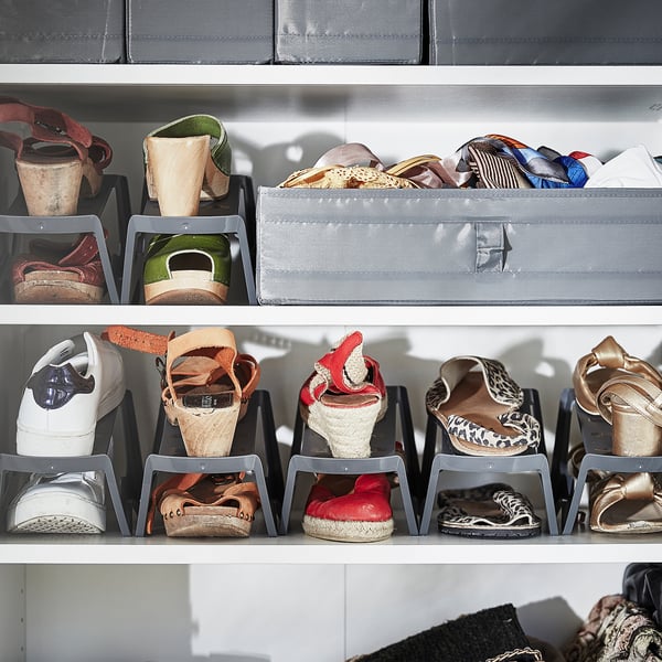 Shoe storage rack with gray organizers holding various footwear styles.