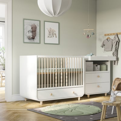 Modern nursery with MYLLRA white cot, green wall prints, hanging light, and changing table. Cot is large, similar to a dresser.