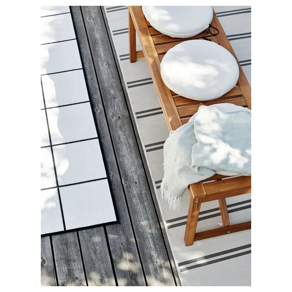Scandinavian-style outdoor wooden furniture set with white cushions and light blue throw.