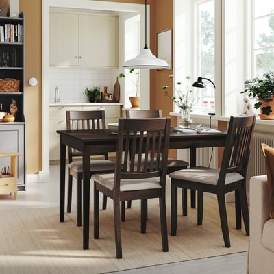 Dark wood NÄSINGE dining set in small kitchen with 4 chairs, lamp, and flowers.