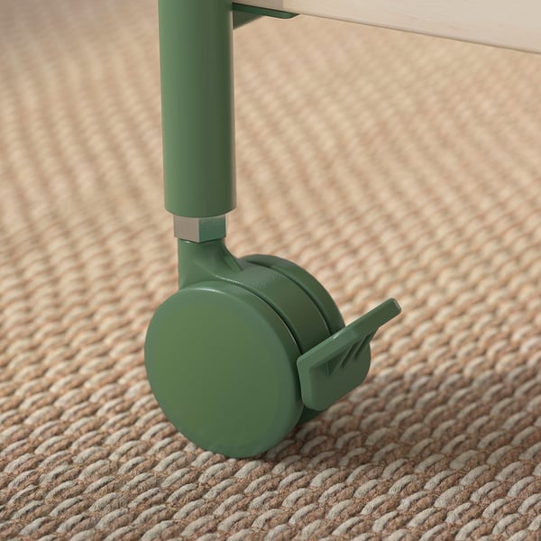 Close-up of a green metal caster wheel attached to a wooden surface. The wheel has a locking mechanism, showcasing its quality and durability.