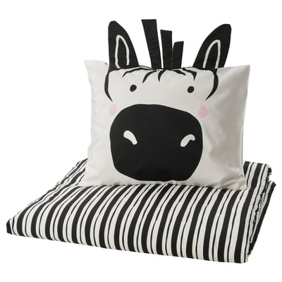 Zebra-themed black & white pillow on striped blanket.
