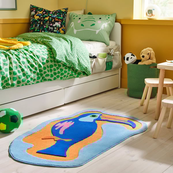 Kids room with natthager rug: blue toucan design, rubber-backed, soft, under bed, with toys.