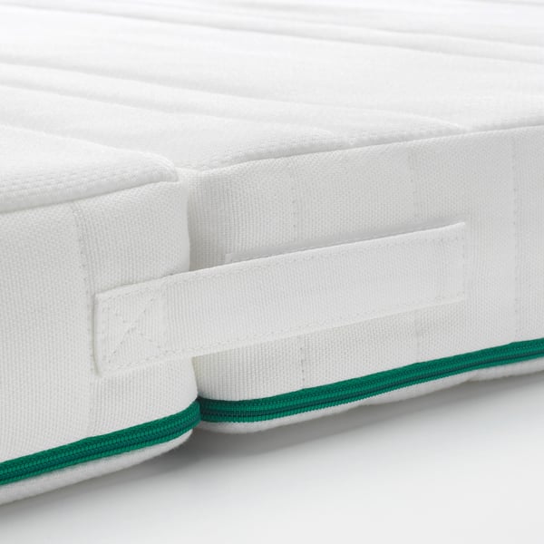 Close-up of a white mattress with green zip detail, showcasing quality craftsmanship and design.
