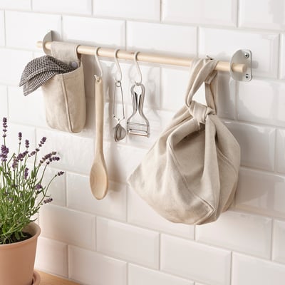 Kitchen wall organiser with hooks and hanging fabric bags, storing utensils and towel.