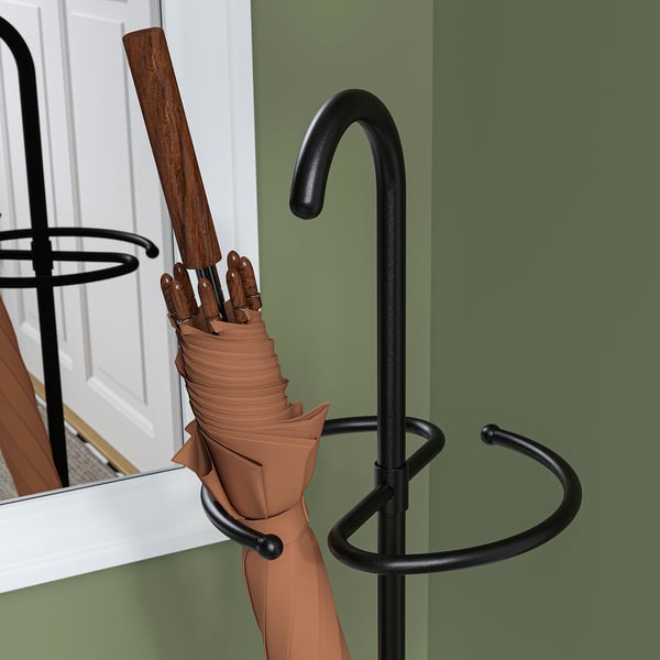 Brown umbrella held by black NIPÅSEN stand against green wall.