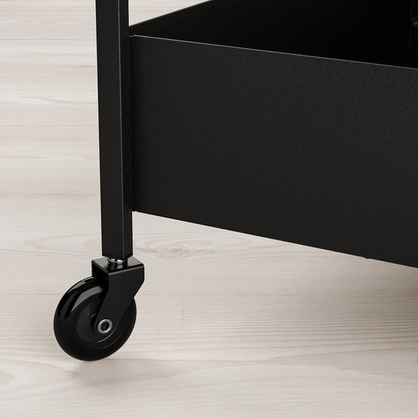 Black metal trolley with caster wheel on wooden floor. Sturdy construction, smooth surface.