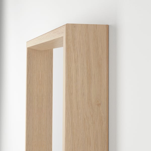 Wooden-framed mirror leaning against white wall, showcasing natural wood grain and craftsmanship.