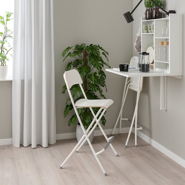 Compact home office: white wall-mounted desk with shelves, chair, and plant. Perfect for small spaces.