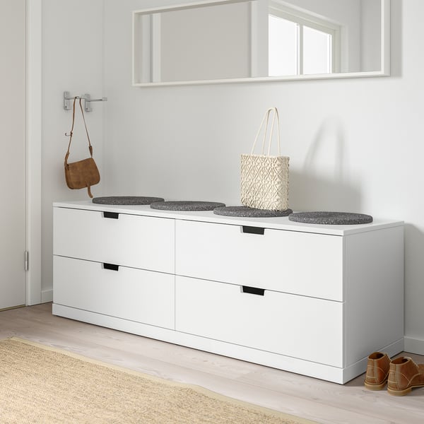 White NORDLI chest with 4 drawers, mirror above, used for seating.
