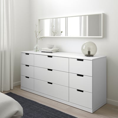 White NORDLI six-drawer chest with black handles, large, minimalist room.
