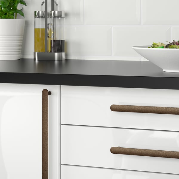 Gold NYDALA kitchen handles, sleek & horizontal, contrast white cabinets & black countertop.