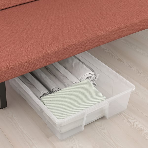 Clear plastic storage box under bed, holding folded linens and items.