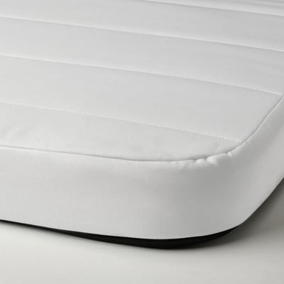 A close-up of a white foam mattress, showing its smooth, covered surface and firm texture.